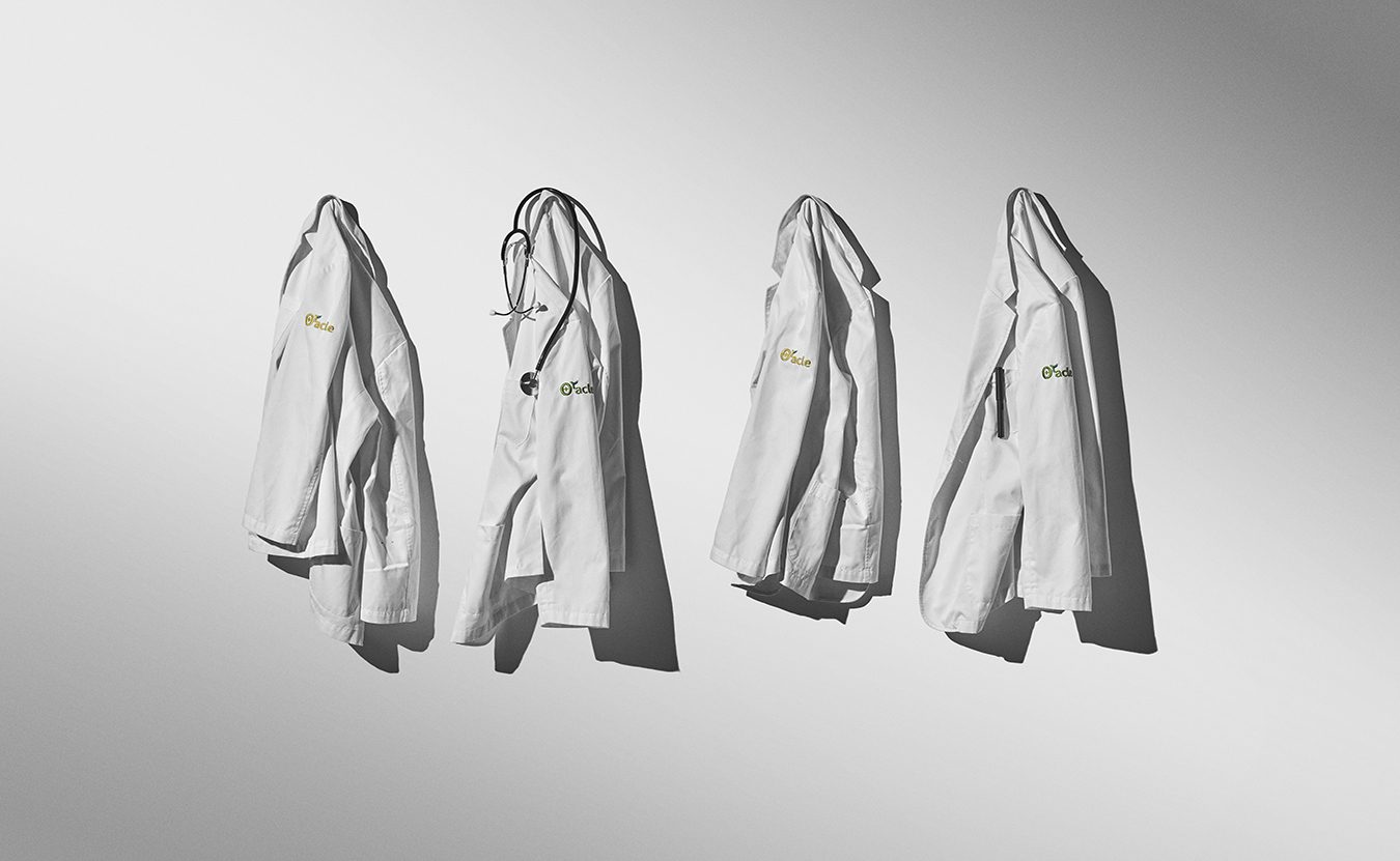 Four white Oracle dermatology clinic coats hanging on a wall